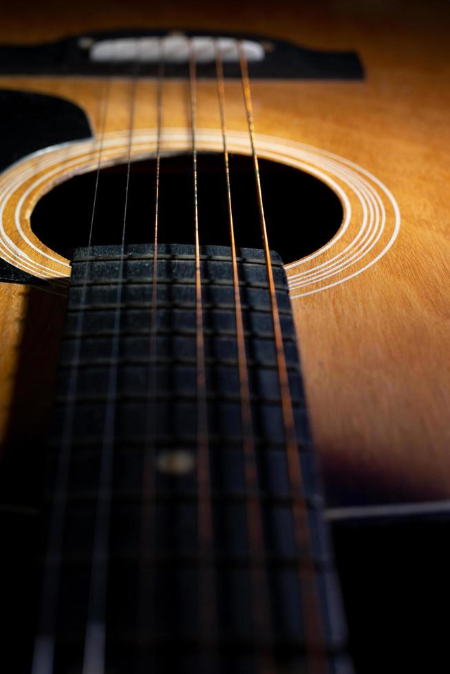 close-up e detalhes do velho violão, linha e curva de instrumento, foco seletivo de cordas de guitarra com escala e pescoço, conceito musical, fundo de guitarra foto