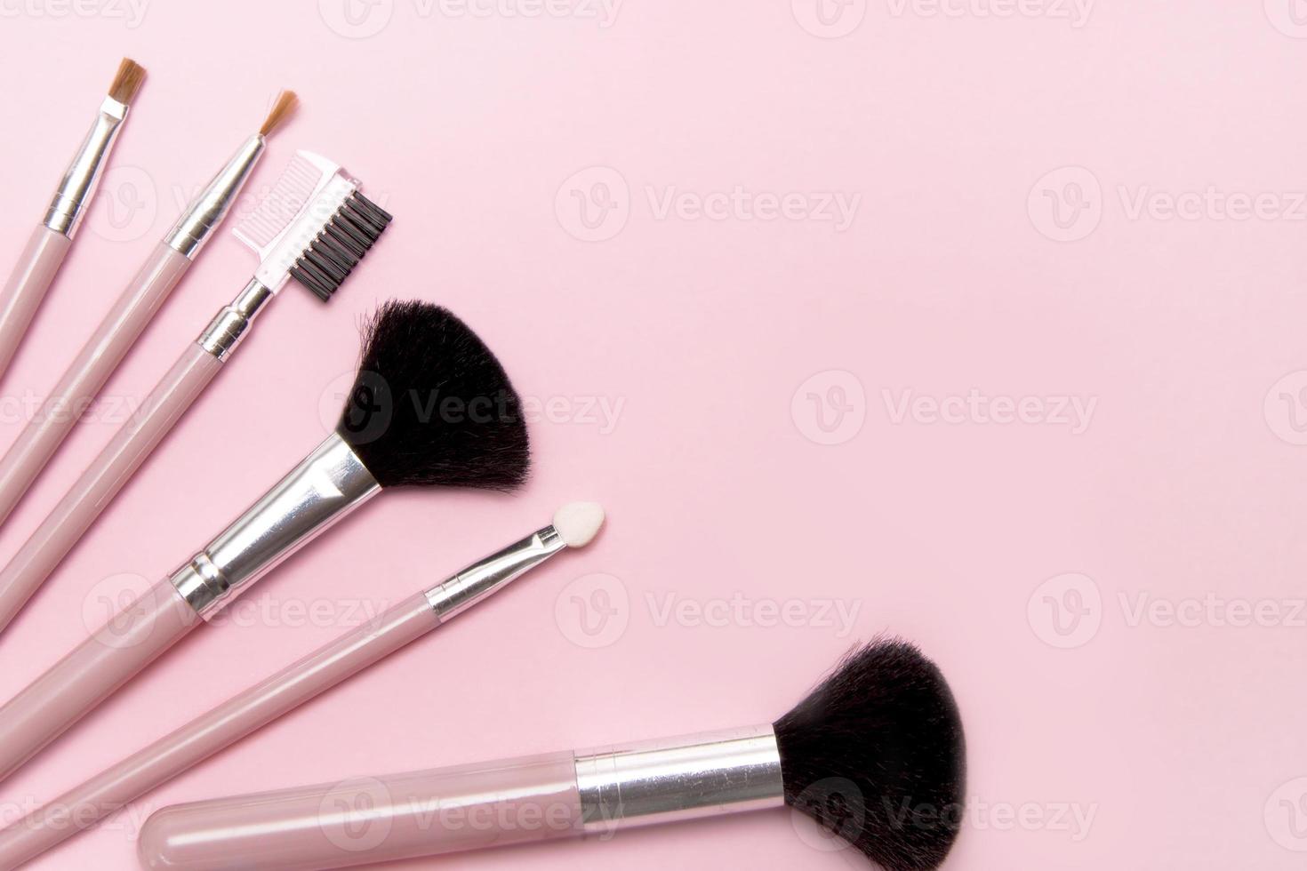 pincéis de maquiagem em fundo rosa com lugar para texto e publicidade foto
