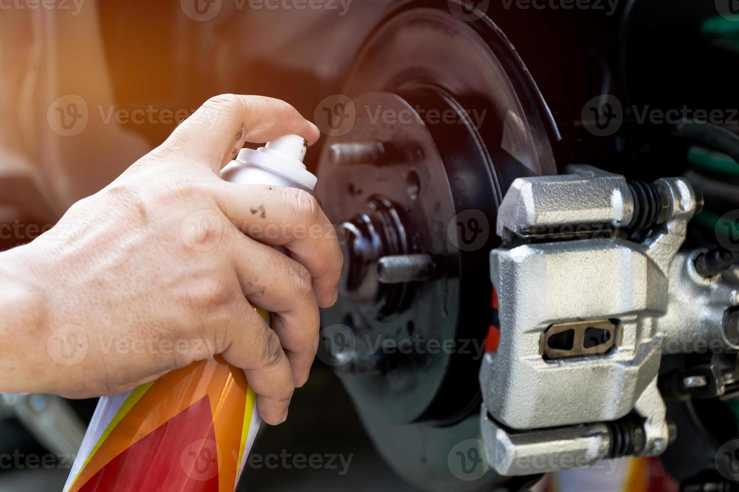 mão um homem usa a placa de freio a disco de reparo de tinta spray da pinça do carro para proteção contra ferrugem foto