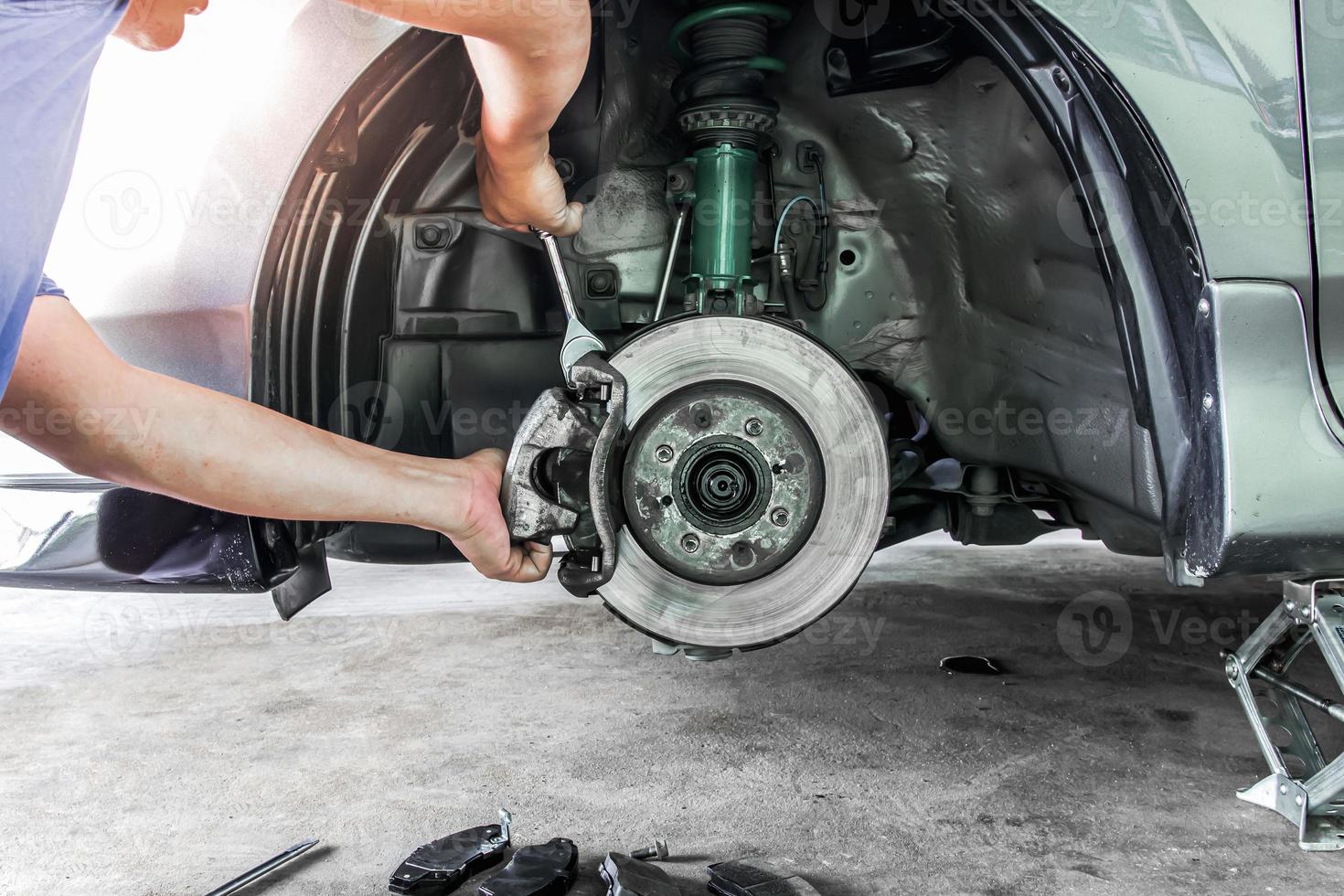 entregar um técnico reparando a ação e o freio a disco de serviço para o carro, troque as pastilhas de freio e verifique o sistema na manutenção básica foto