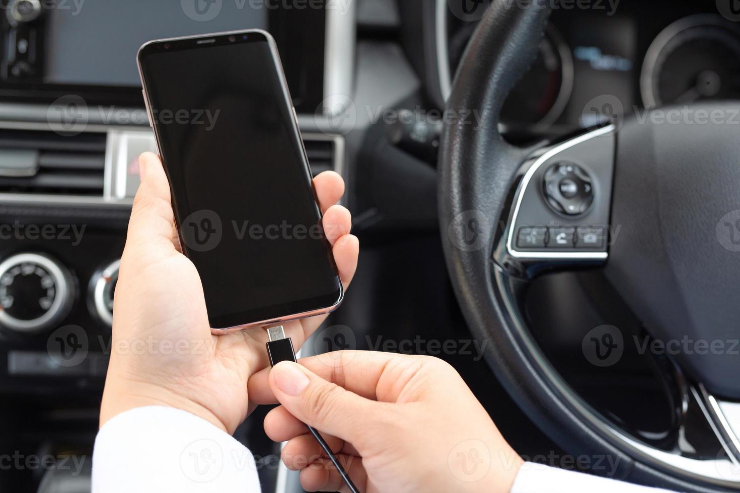 close-up e um homem usa o plugue do cabo para carregar o celular no carro,  conectando o jogo de dados do carro, música, sistema de navegação e  carregamento do celular em processo