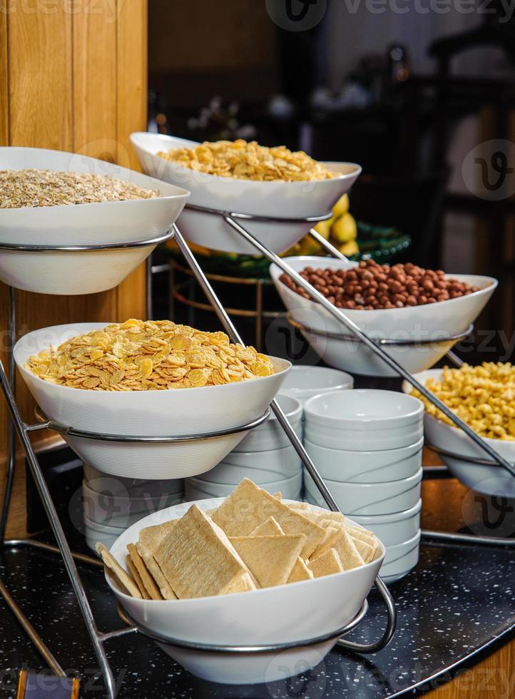 um tiro vertical de uma mesa de buffet cheia de tigelas com flocos de milho, amendoim e cereais no café da manhã foto