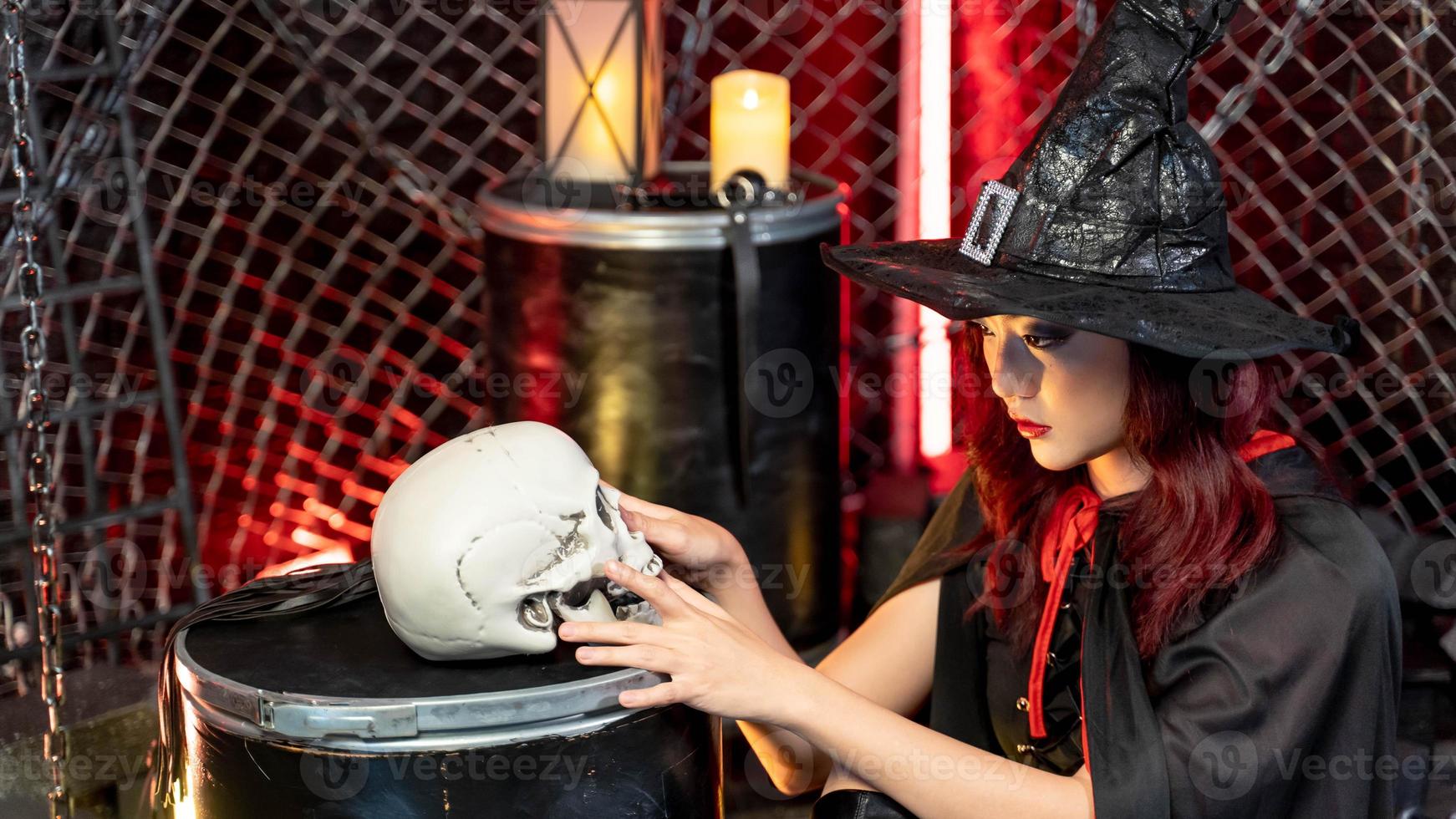 linda mulher vestindo fantasia de bruxa para halloween procurando um crânio humano foto