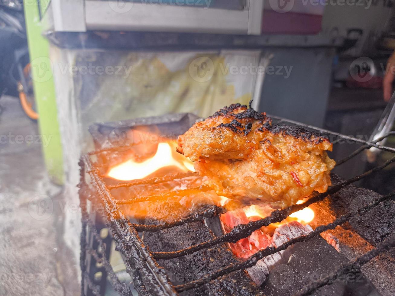 peito de frango envolto em farinha crocante com deliciosos temperos picantes grelhados em carvão quente fumegante. um típico frango grelhado da indonésia foto