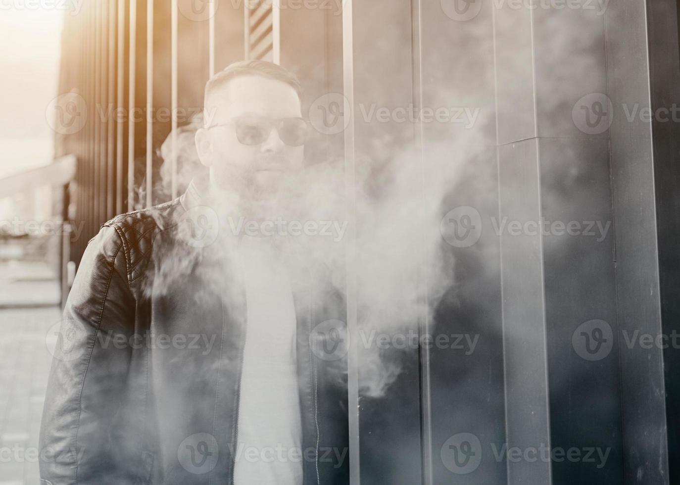 cara bonito fumando um cigarro eletrônico foto