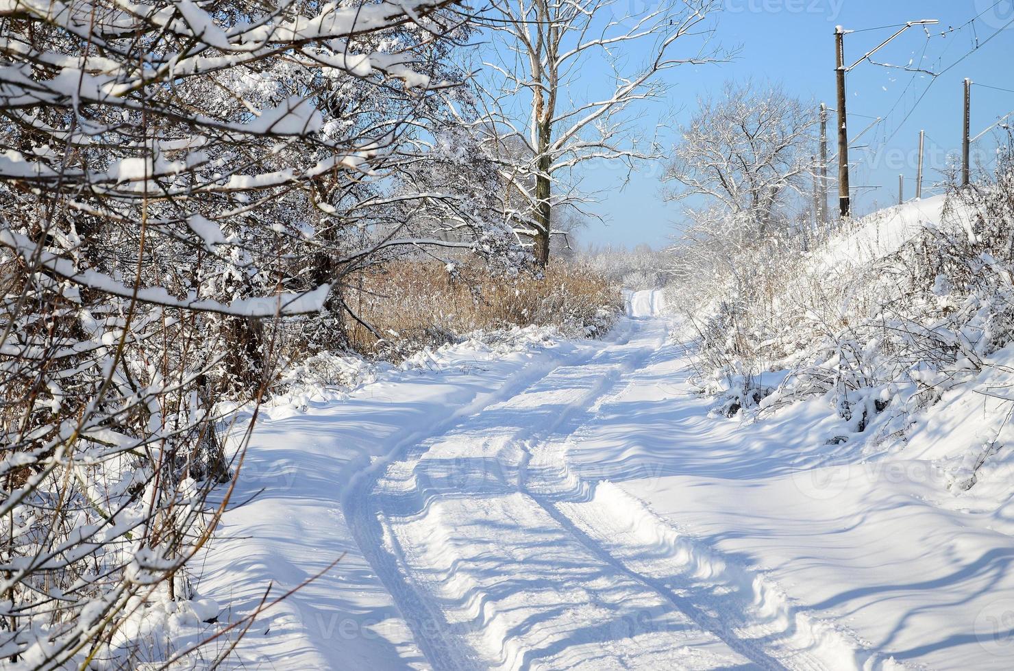 a estrada paralela à linha férrea está coberta de neve em um dia ensolarado após uma forte nevasca foto