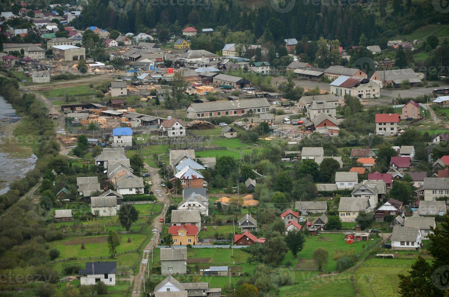 uma bela vista da vila de mezhgorye, região dos cárpatos. muitos edifícios residenciais cercados por altas montanhas da floresta e longo rio foto