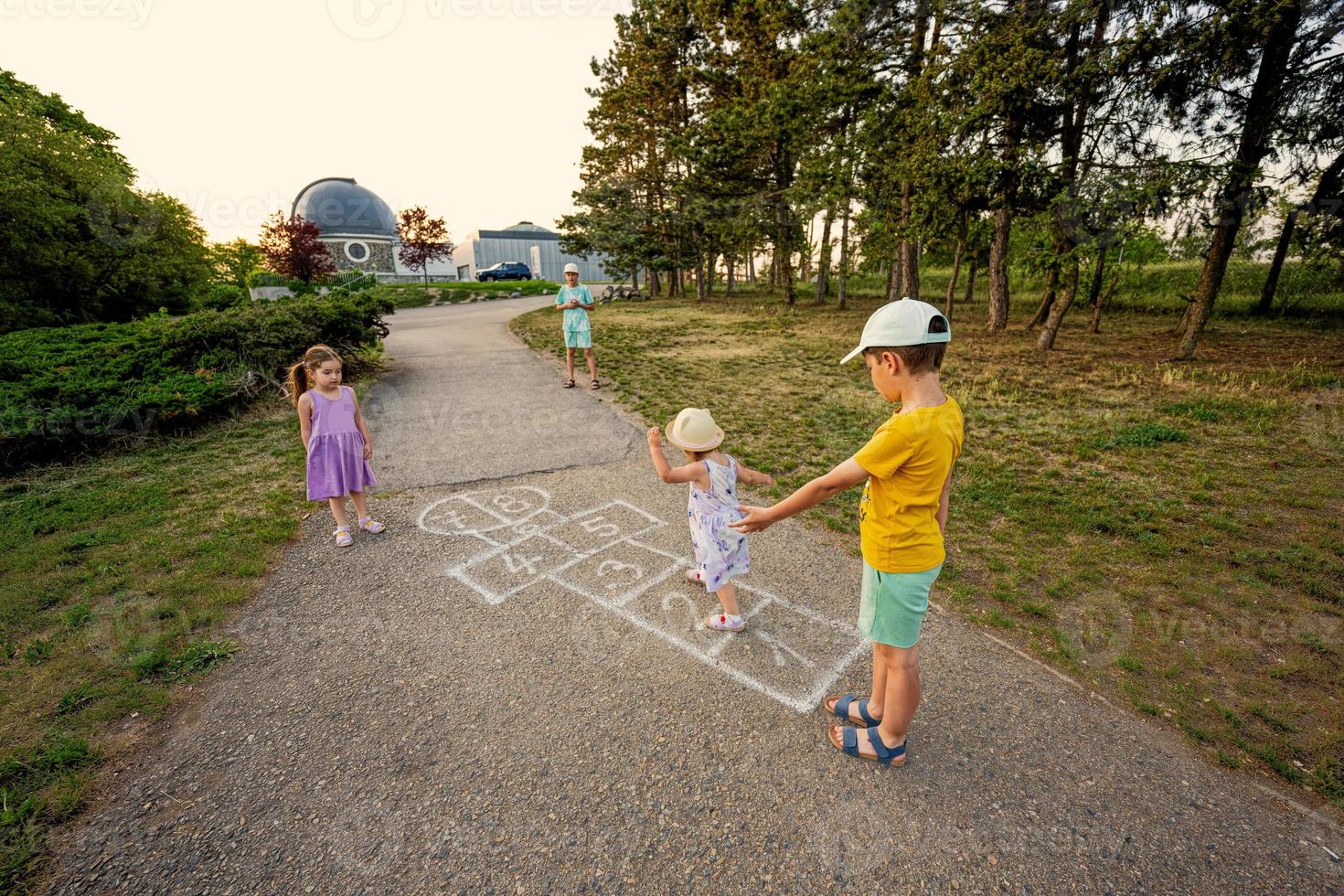 crianças brincando de amarelinha no parque. crianças atividades ao ar livre. foto