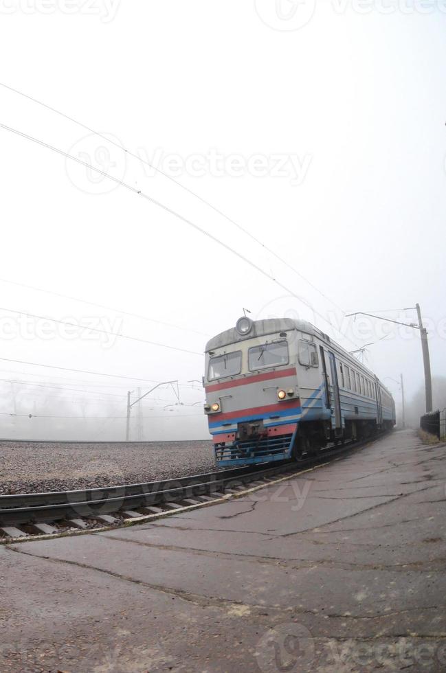 o trem suburbano ucraniano corre ao longo da ferrovia em uma manhã nublada. foto olho de peixe com distorção aumentada