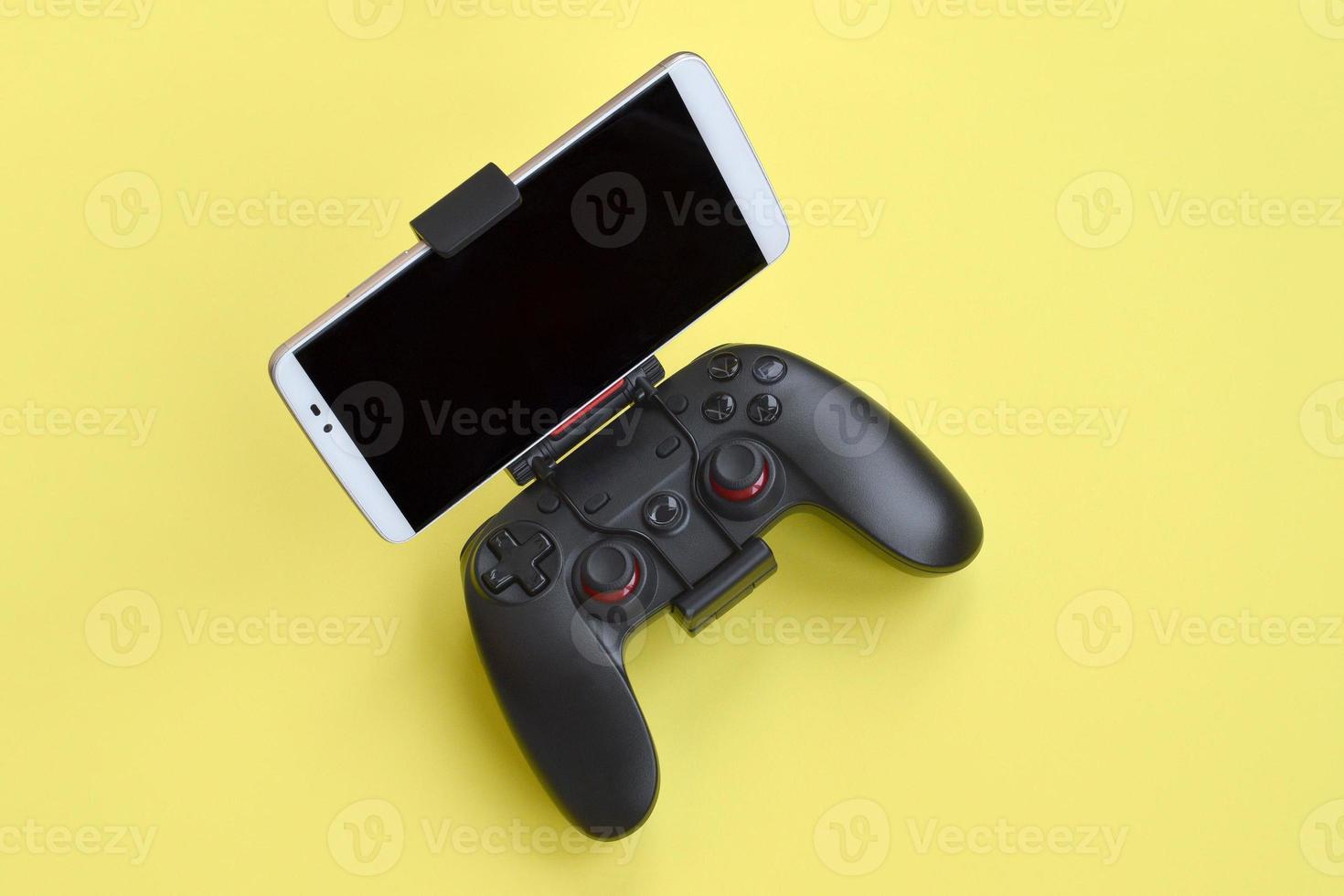 gamepad preto moderno para smartphone em fundo amarelo. dispositivo de jogo de vídeo móvel foto