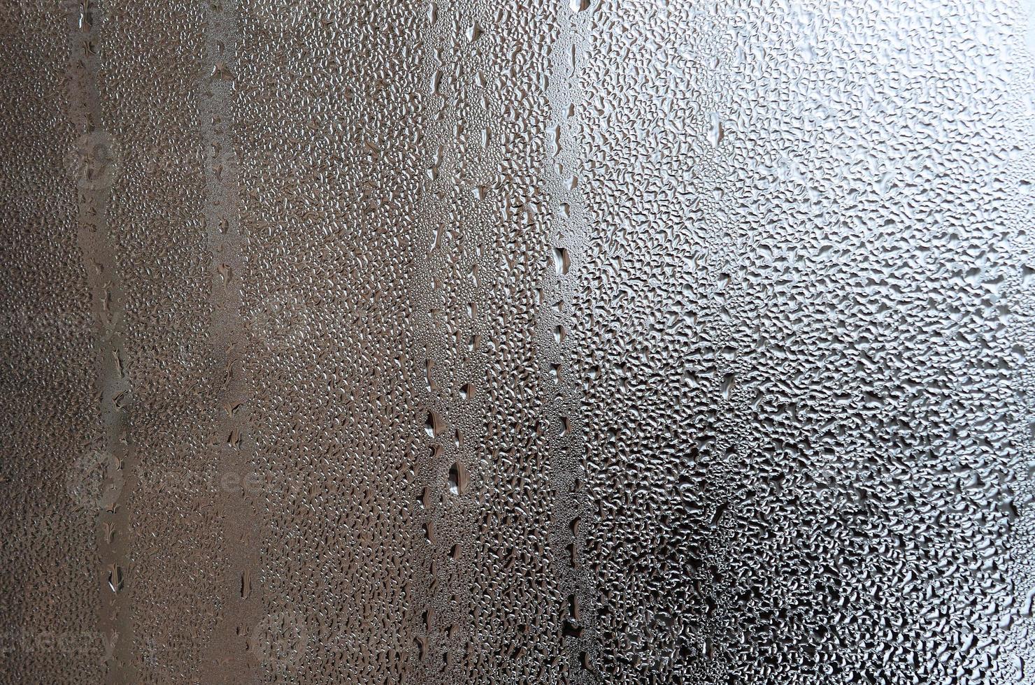 textura de uma gota de chuva em um fundo transparente de vidro molhado. tonificado na cor cinza foto