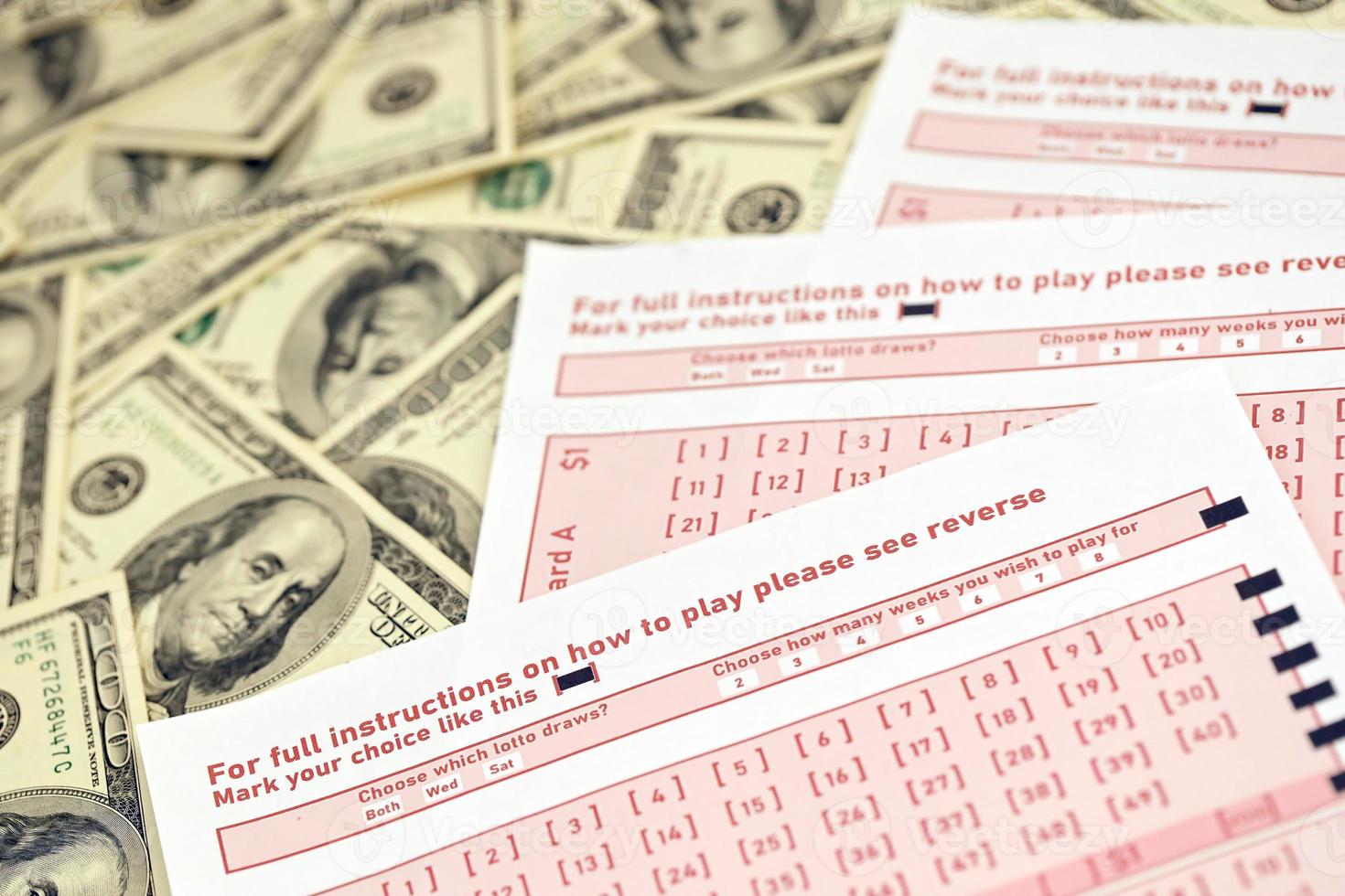 folhas de jogo rosa com números para marcação em grande quantidade de notas de cem dólares. conceito de jogo de loteria ou vício em jogos de azar. fechar-se foto