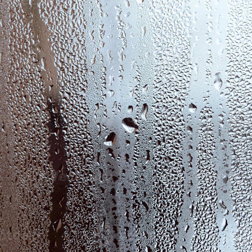 textura de uma gota de chuva em um fundo transparente de vidro molhado. tonificado na cor cinza foto