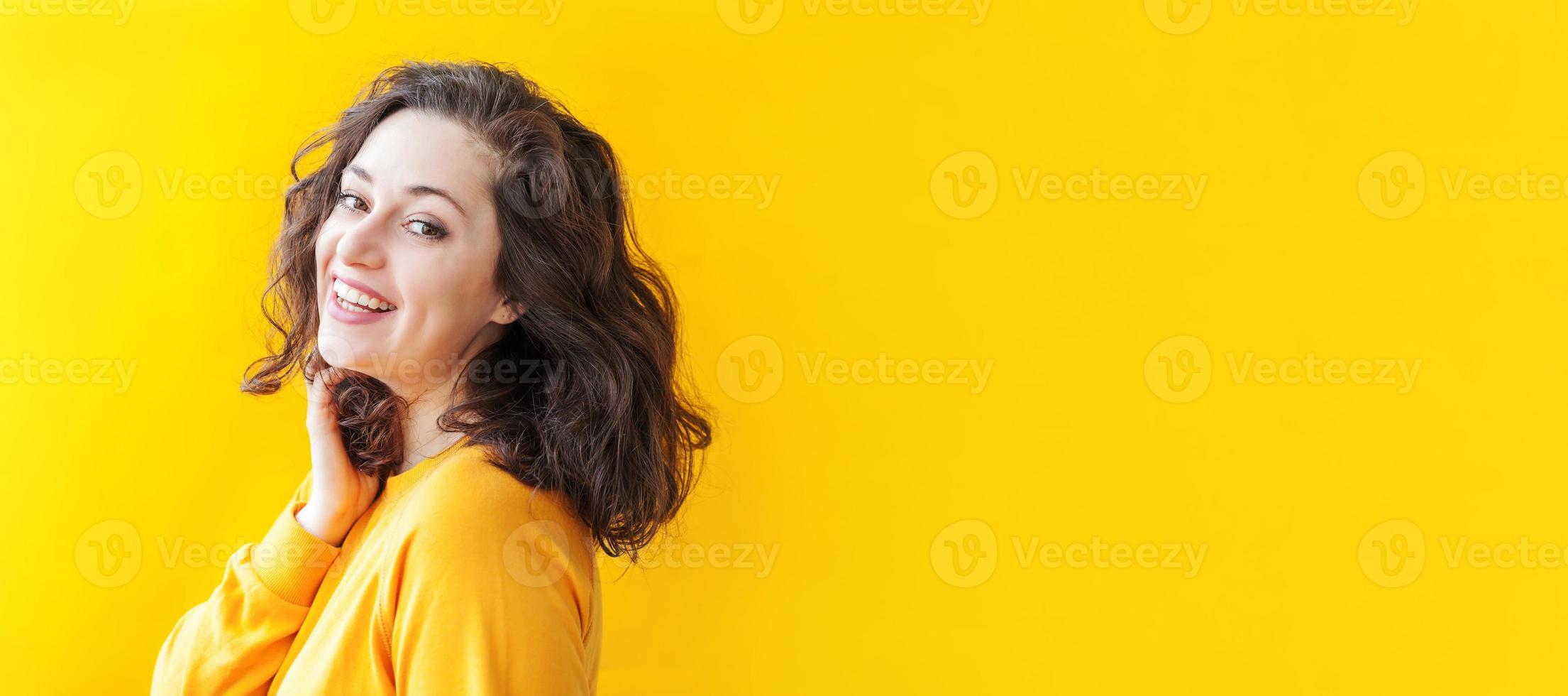 garota feliz sorrindo. beleza retrato jovem feliz positivo rindo morena sobre fundo amarelo isolado. mulher europeia. emoção humana positiva expressão facial linguagem corporal foto