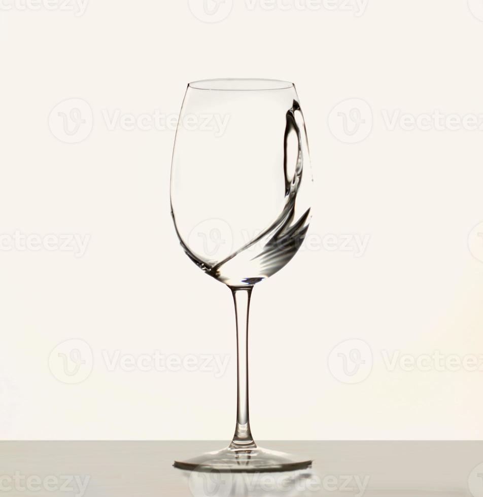 um pouco de vinho branco em um copo de vinho. respingos de água. água potável. álcool. isolado no fundo branco foto