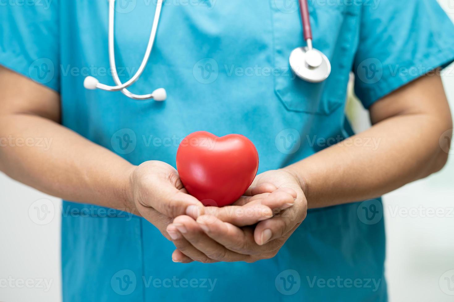 médico segurando um coração vermelho na enfermaria do hospital, conceito médico forte e saudável. foto