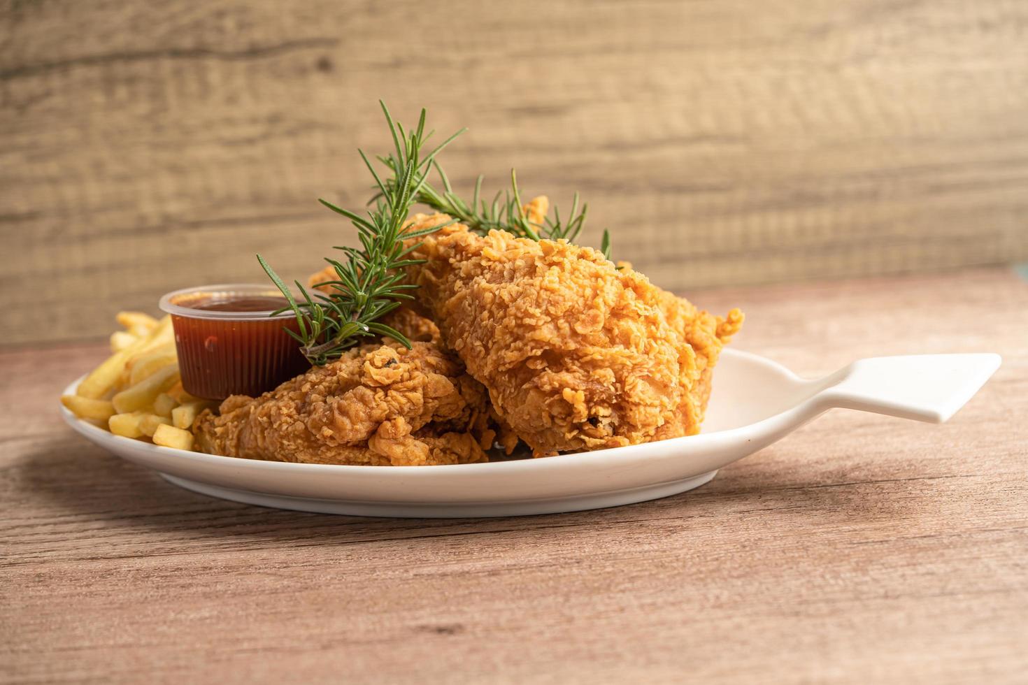 Frango frito e batata frita com folha de alecrim, junk food de alto teor calórico servido no prato branco foto