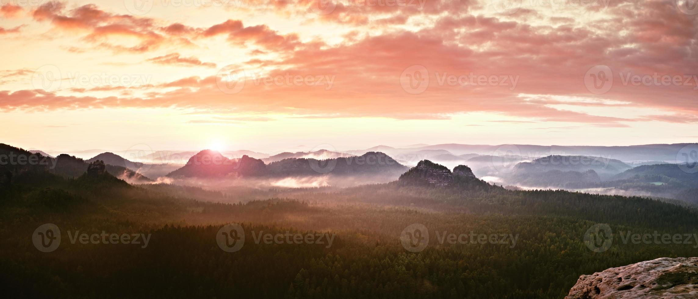 panorama da paisagem enevoada vermelha nas montanhas. nascer do sol fantástico e sonhador foto