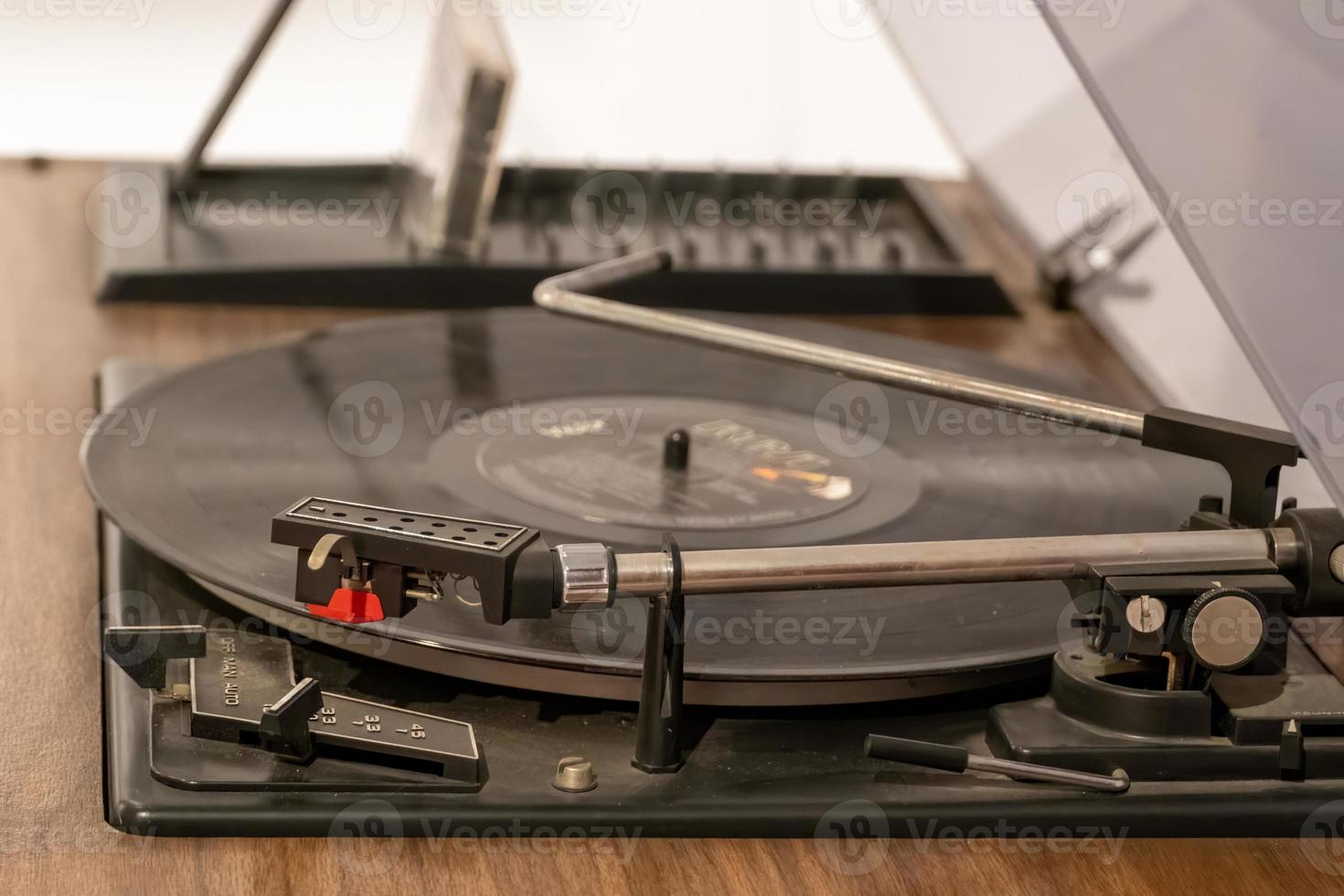 toca-discos de vinil de plataforma giratória com discos de vinil em uma mesa de madeira. disco de vinil preto foto