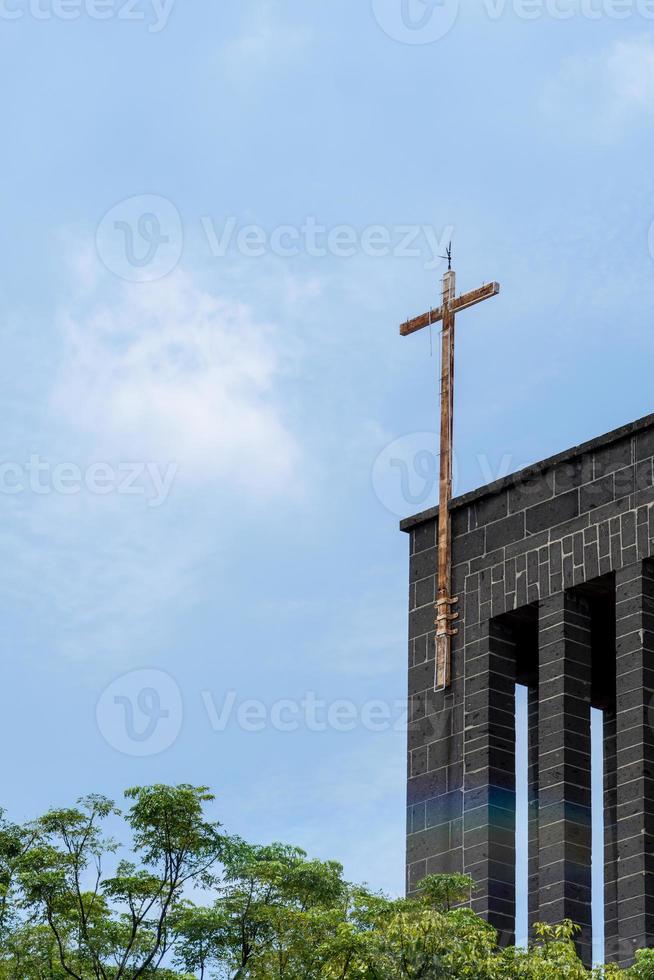 topo de uma igreja com uma cruz de metal enferrujada, a igreja é feita de pedra com céu azul claro. México foto
