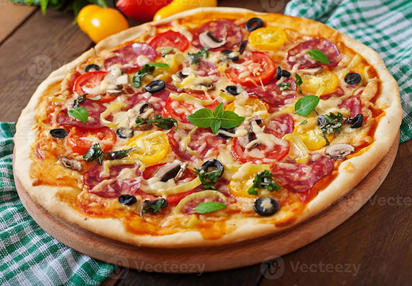 pizza com salame, tomate, queijo e azeitonas foto