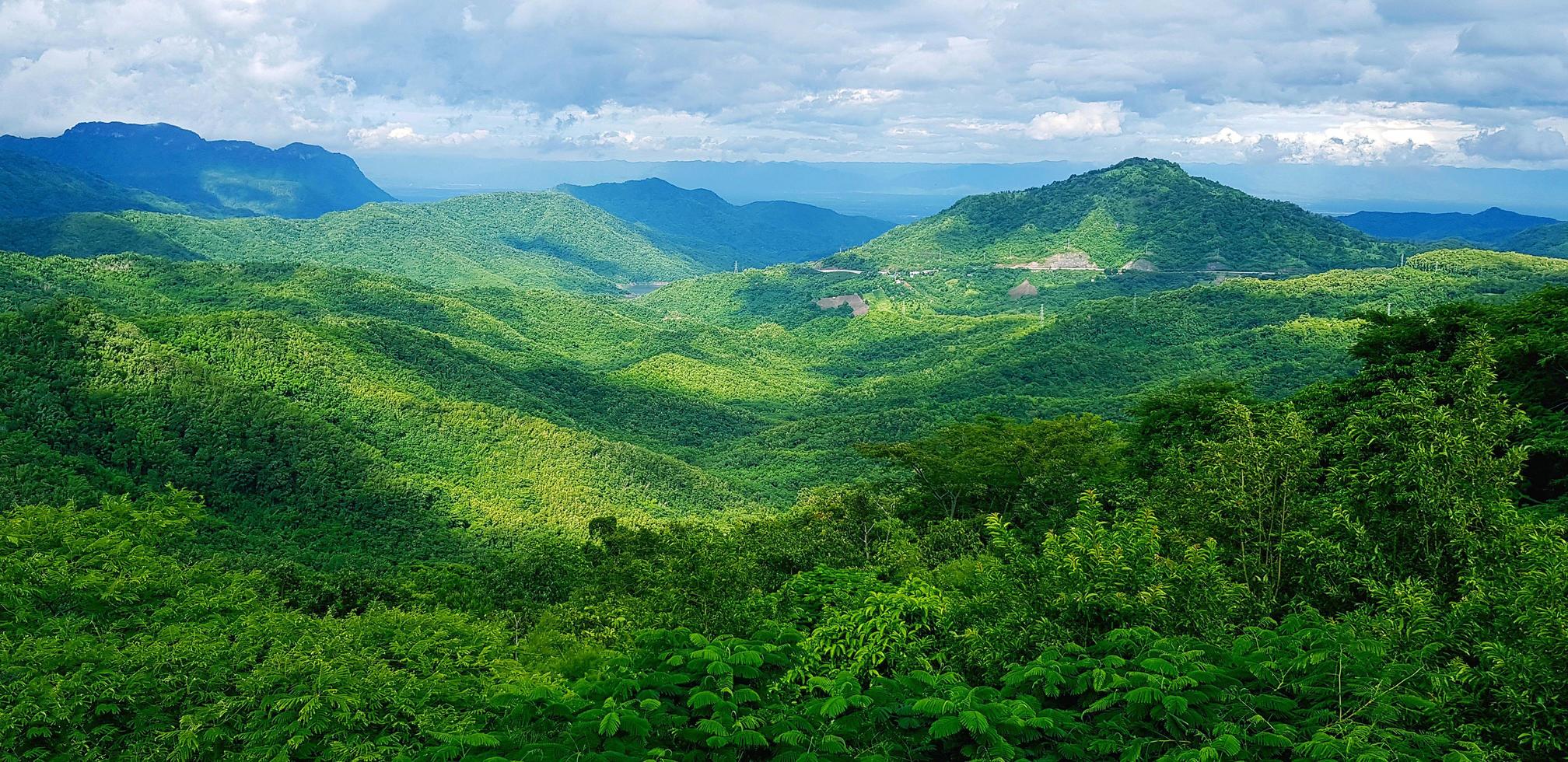 bela paisagem de montanha. floresta verde ou selva profunda com salto de montanha e céu de nuvens. beleza da natureza e conceito de papel de parede natural foto