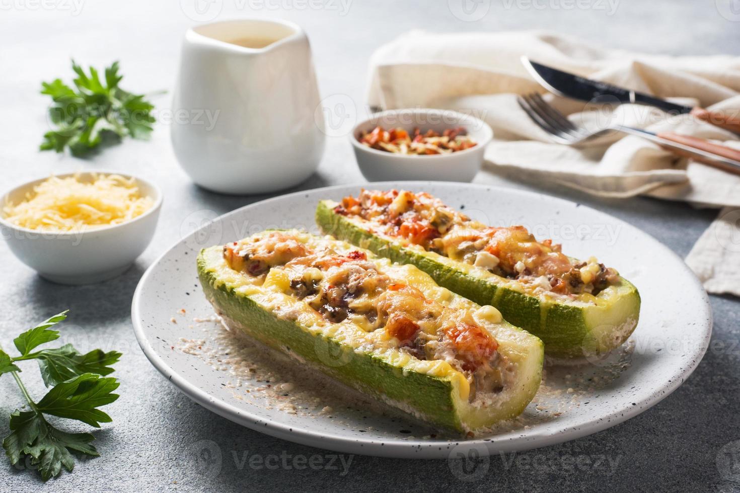 Barcos de abobrinha recheados assados com cogumelos de frango picado e legumes com queijo em um prato. foto