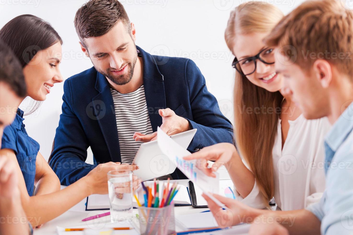 debate. grupo de empresários alegres em roupas casuais inteligentes trabalhando juntos enquanto está sentado à mesa foto