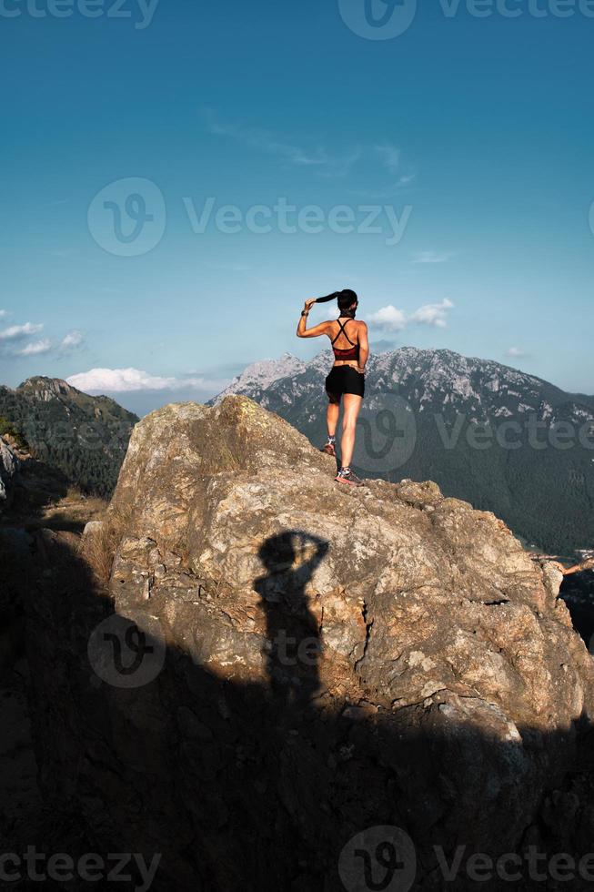 sombra de um fotógrafo retratando uma desportista em uma rocha foto