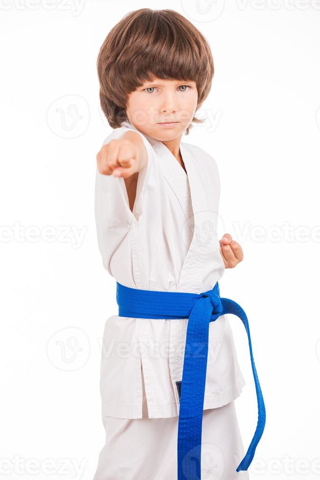garoto de karatê. garotinho fazendo movimentos de artes marciais enquanto isolado no fundo branco foto