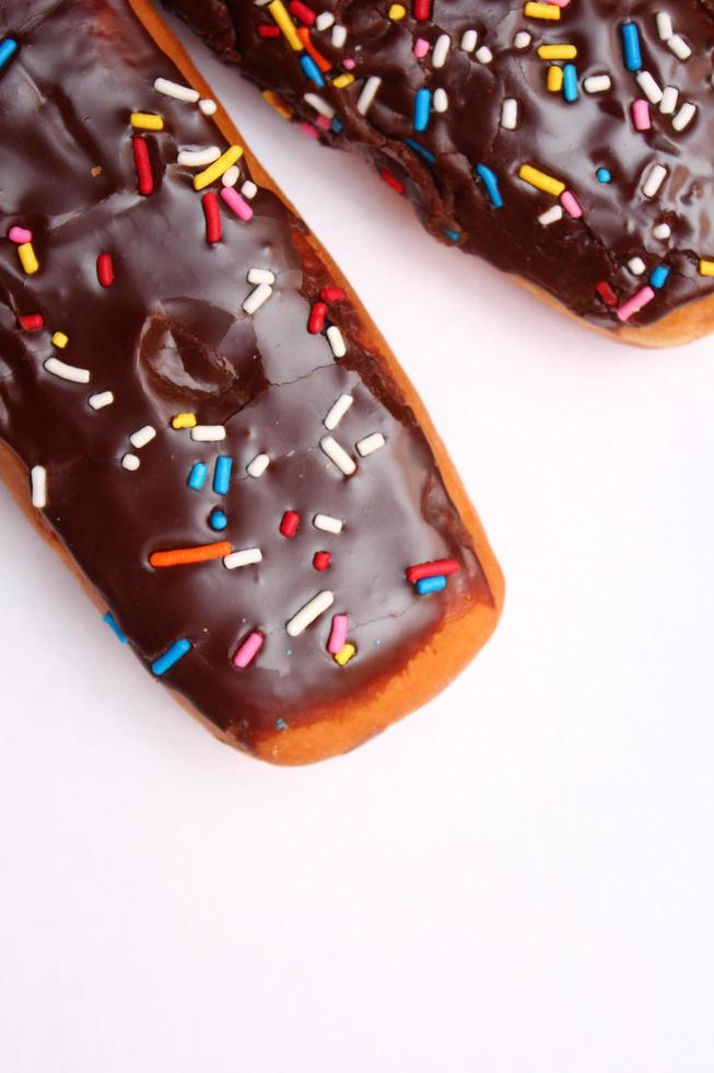 barra de rosquinha de chocolate coberta com flocos de açúcar multicoloridos. colocado em um fundo branco foto