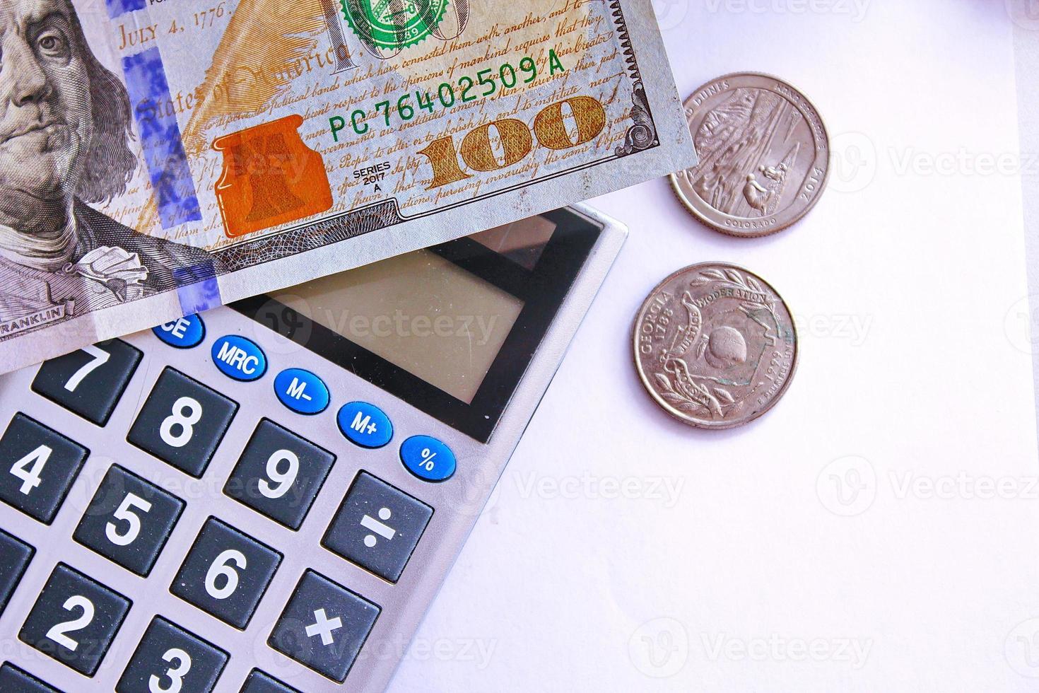 calculadora e notas de dólar são colocadas em uma mesa branca. foto