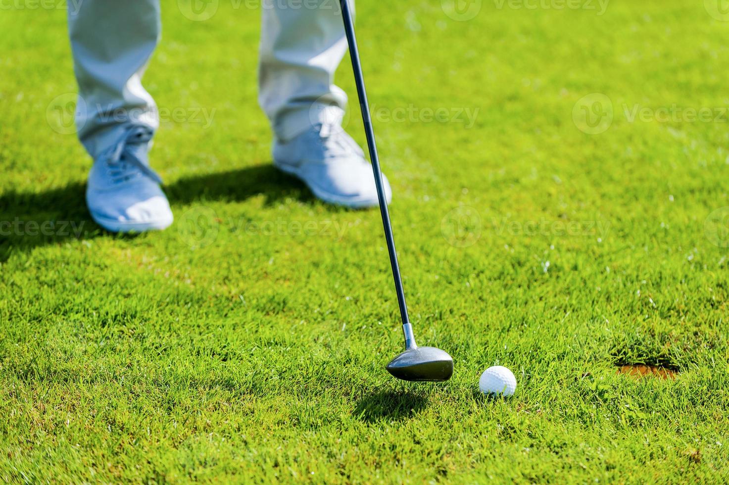 quase dentro close-up de homem jogando golfe em pé no verde e perto do buraco foto