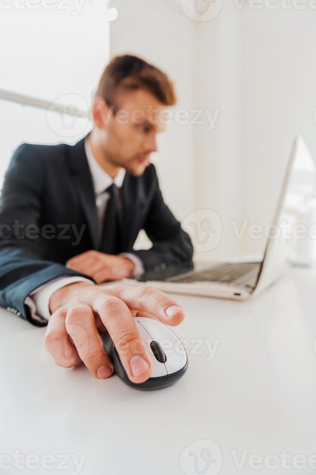 um toque e o trabalho está concluído. jovem confiante em trajes formais trabalhando no laptop em seu local de trabalho foto