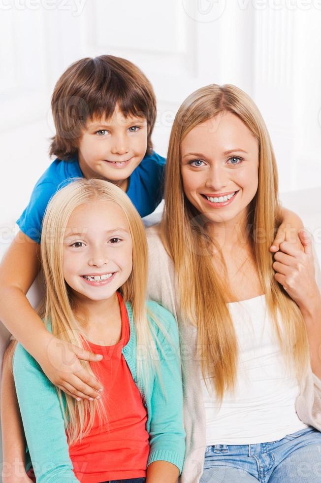 nossa mãe é a melhor vista de cima da mãe feliz e dois filhos pequenos se unindo e sorrindo enquanto estão sentados no sofá juntos foto