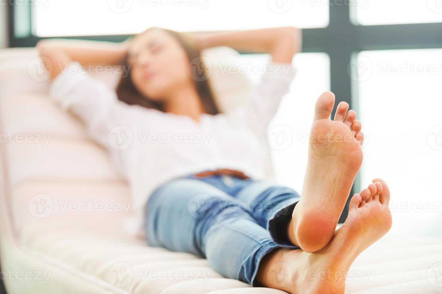 tendo tempo para relaxar. bela jovem segurando as mãos atrás da cabeça enquanto dormia no sofá foto