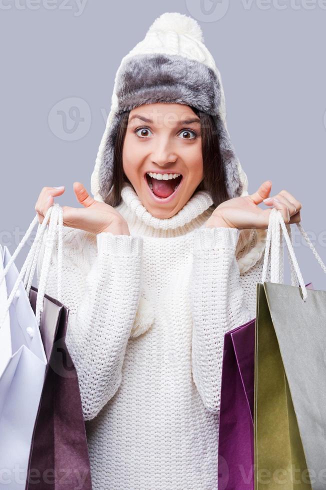 tempo para presentes. mulheres jovens felizes vestindo roupas quentes de inverno e segurando pacotes com compras em pé contra um fundo cinza foto