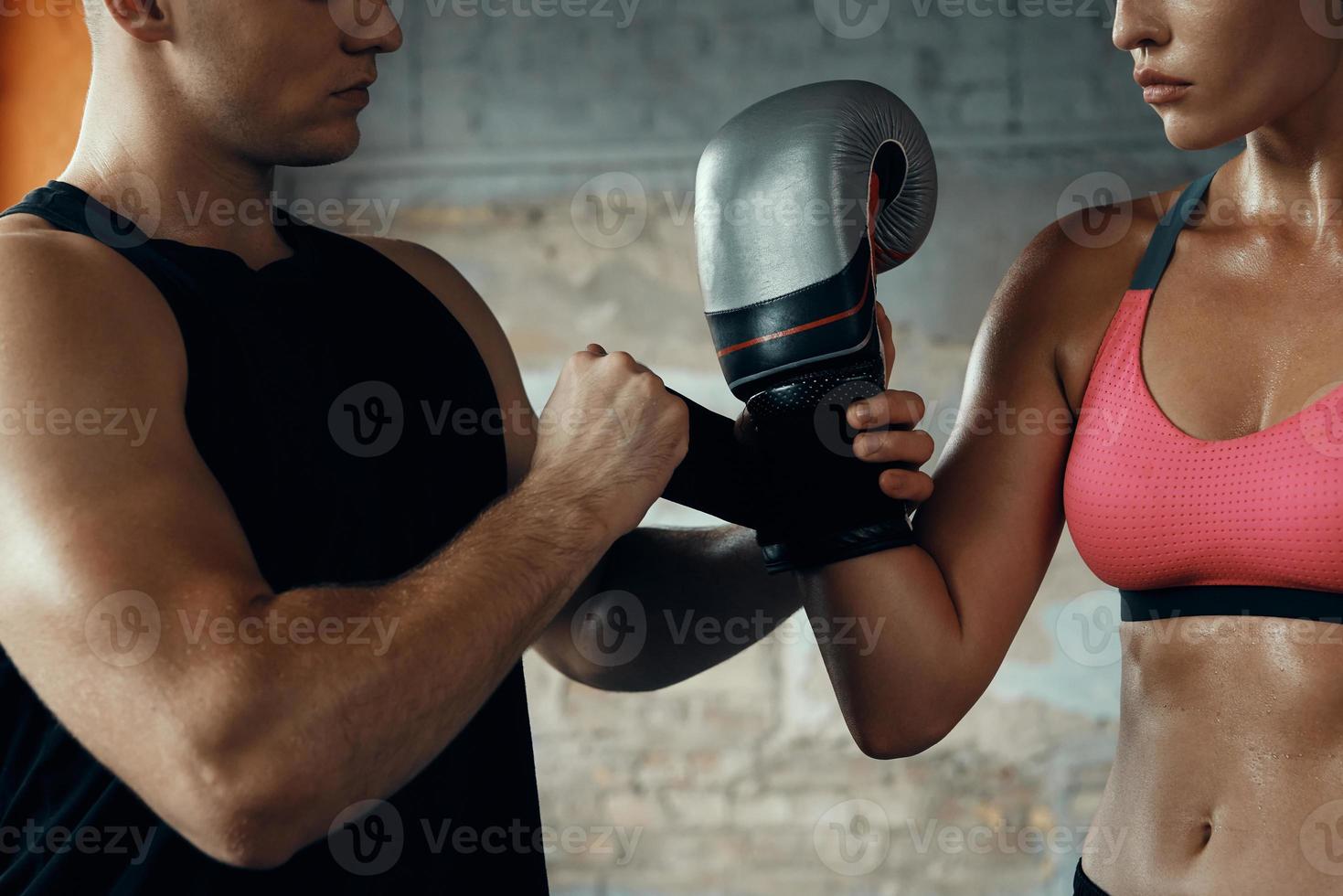 close-up de treinador masculino ajudando jovem a usar luva de boxe no ginásio foto