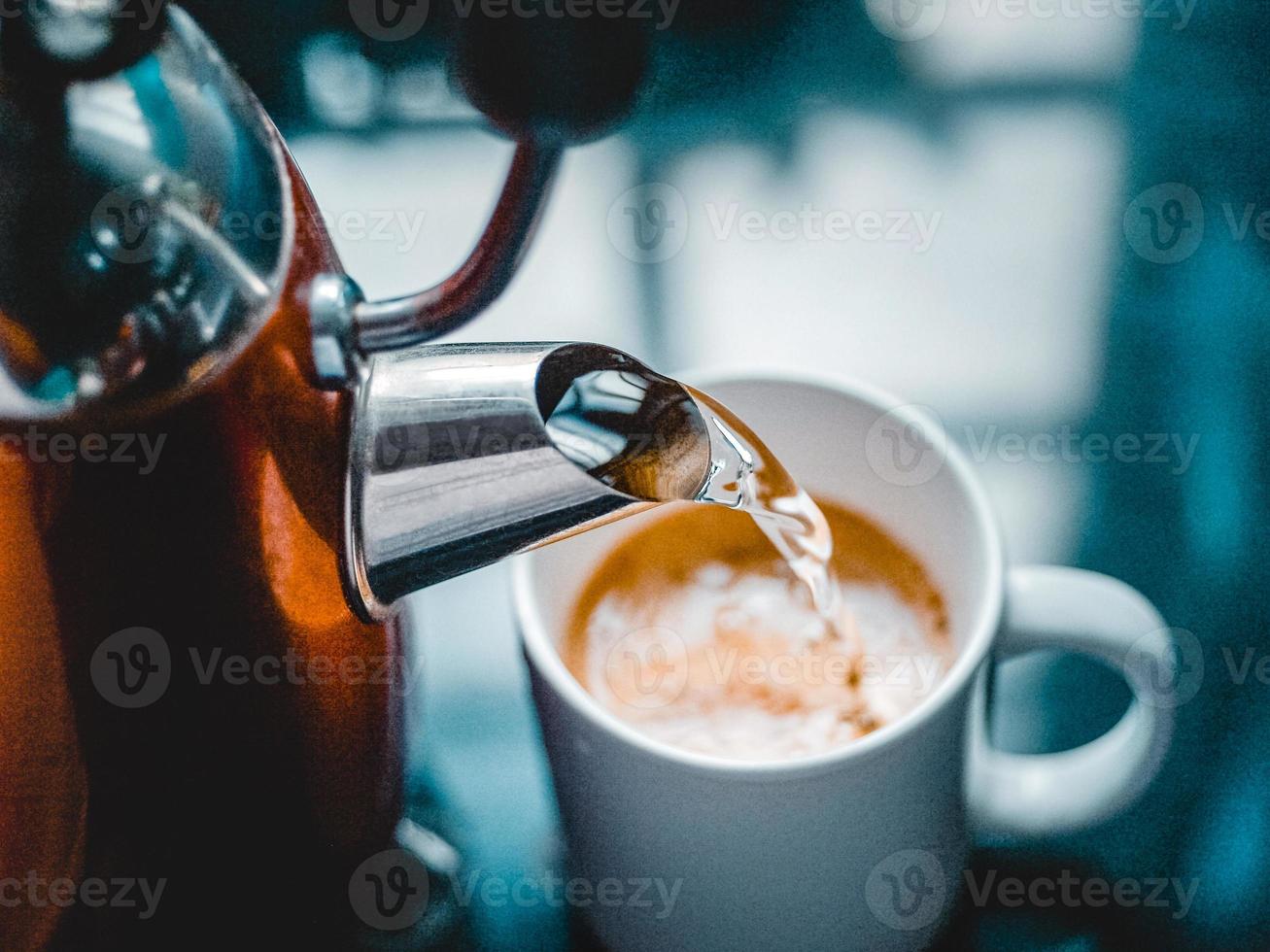 derramando água quente em uma caneca para café foto