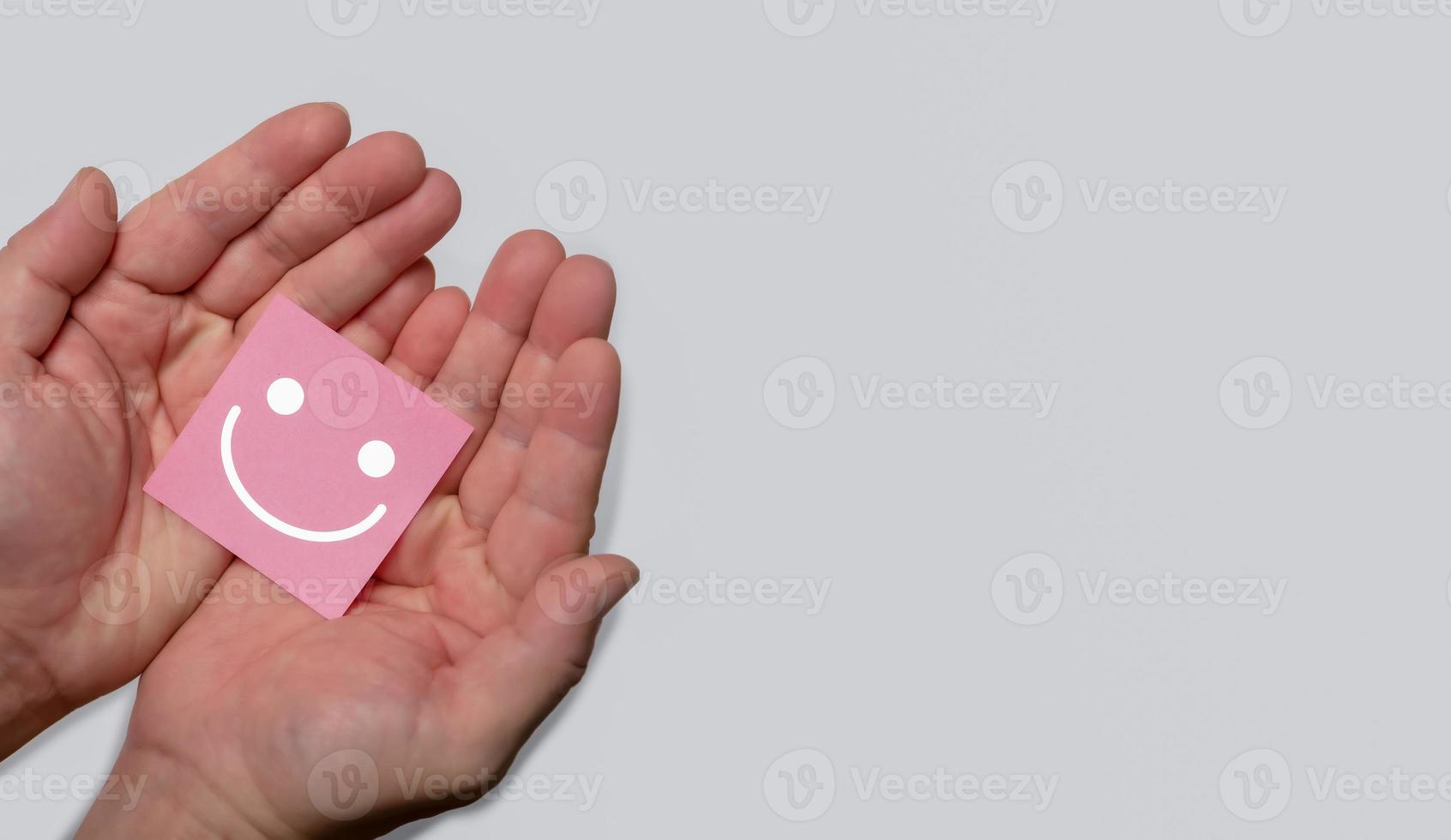 conceito de satisfação de revisão do cliente, mão segurando o ícone de rosto sorridente de emoção positiva com espaço de cópia. foto
