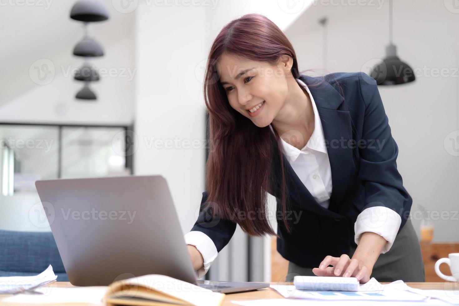 mulher de negócios asiática usando calculadora e laptop para fazer finanças matemáticas em uma mesa de escritório, imposto, relatório, contabilidade, estatística e conceito de pesquisa analítica foto