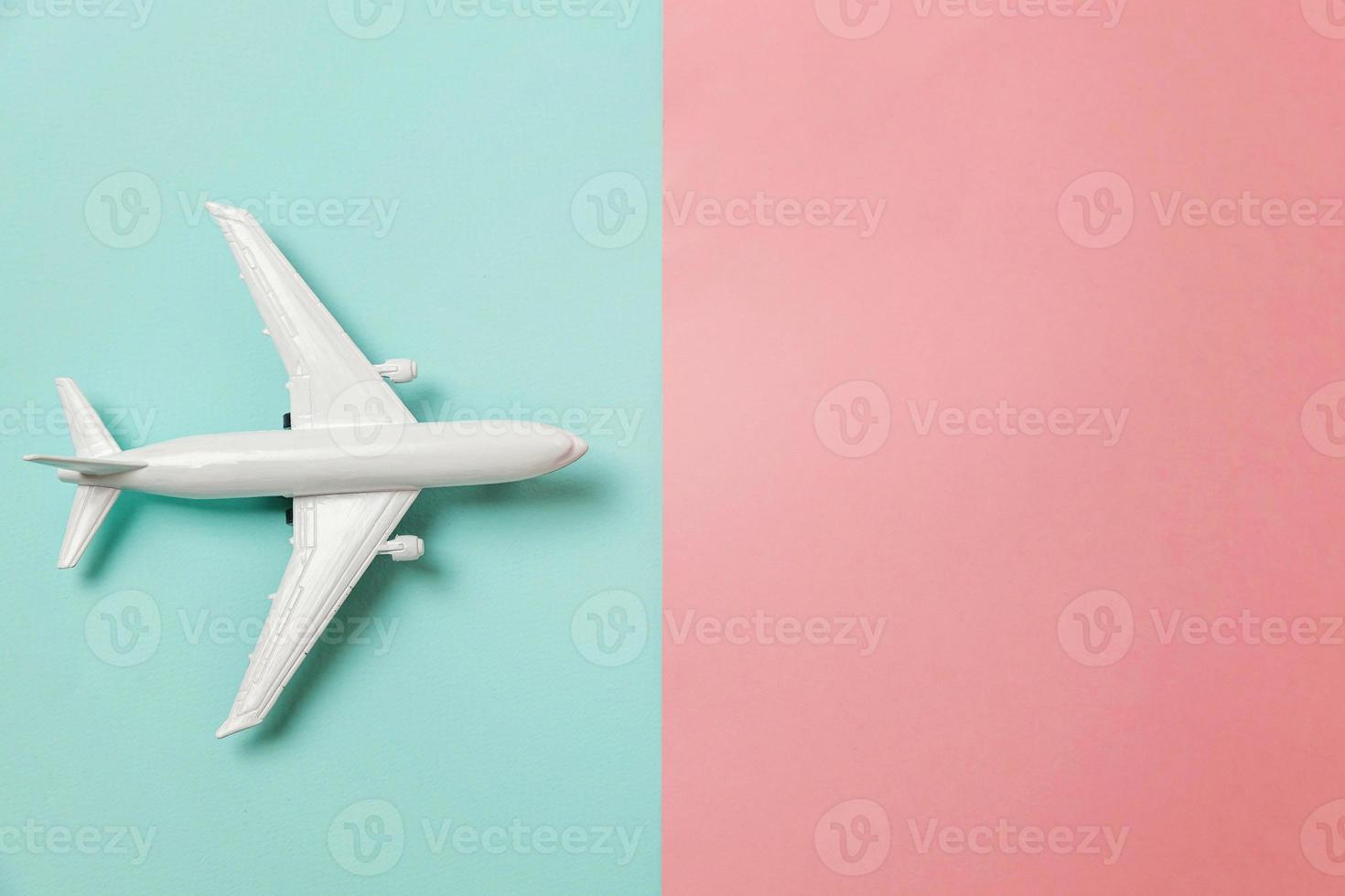 avião de modelo de brinquedo em miniatura de design simplesmente plano leigo em fundo geométrico moderno de papel colorido pastel azul e rosa. viajar de avião férias verão fim de semana mar aventura viagem conceito. foto