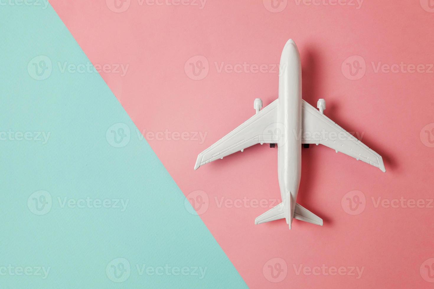 avião de modelo de brinquedo em miniatura de design simplesmente plano leigo em fundo geométrico moderno de papel colorido pastel azul e rosa. viajar de avião férias verão fim de semana mar aventura viagem conceito. foto