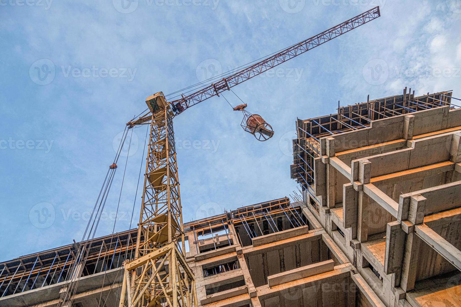 um tiro de ângulo baixo de um guindaste com equipamento em um canteiro de obras com uma nova infraestrutura de construção. despejando concreto em um molde foto