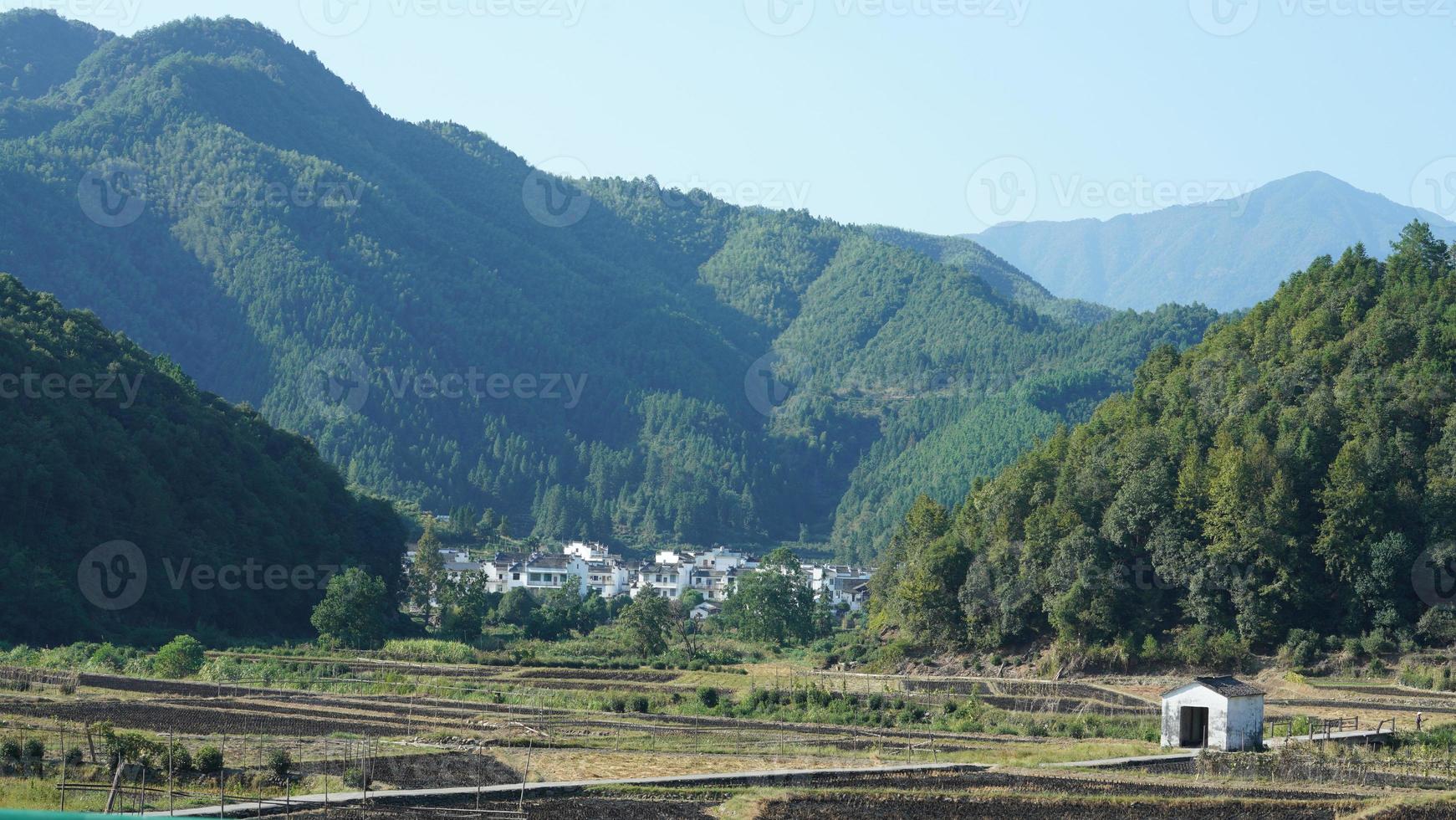 as belas paisagens de montanhas com a floresta verde e a pequena vila como pano de fundo no interior da China foto