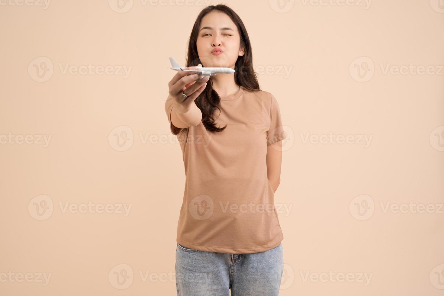 jovem feliz em pé e segurando um sonhador de avião de brinquedo branco no estúdio foto