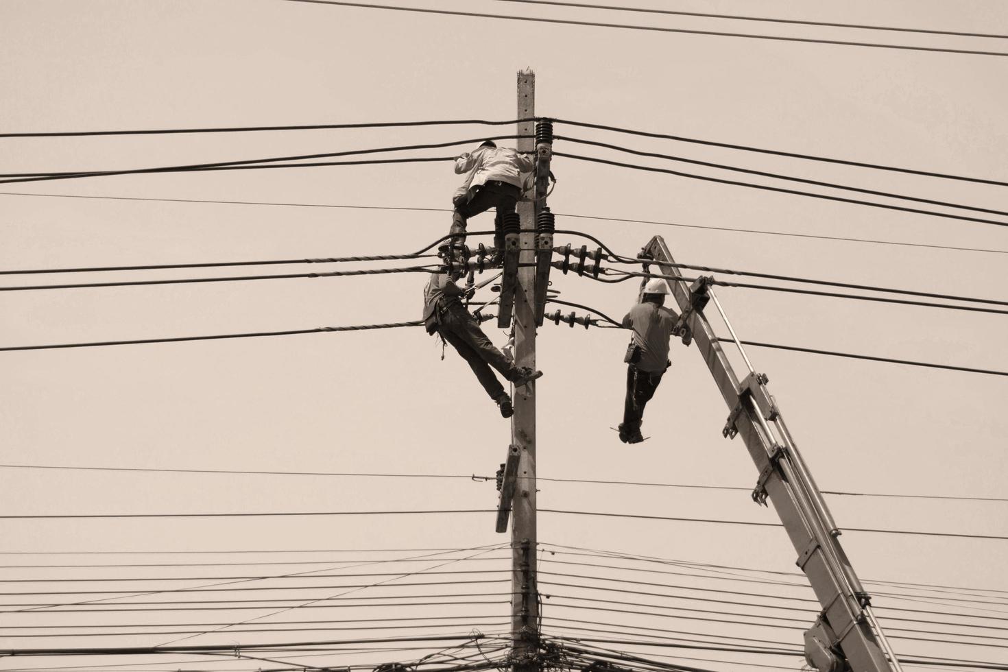 homens trabalhando em poste elétrico foto