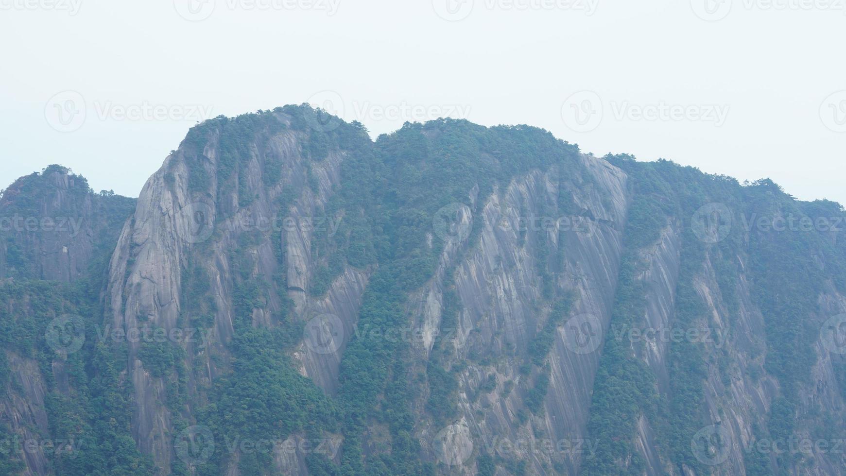 as belas paisagens das montanhas com a floresta verde e o penhasco rochoso em erupção como pano de fundo na zona rural da china foto