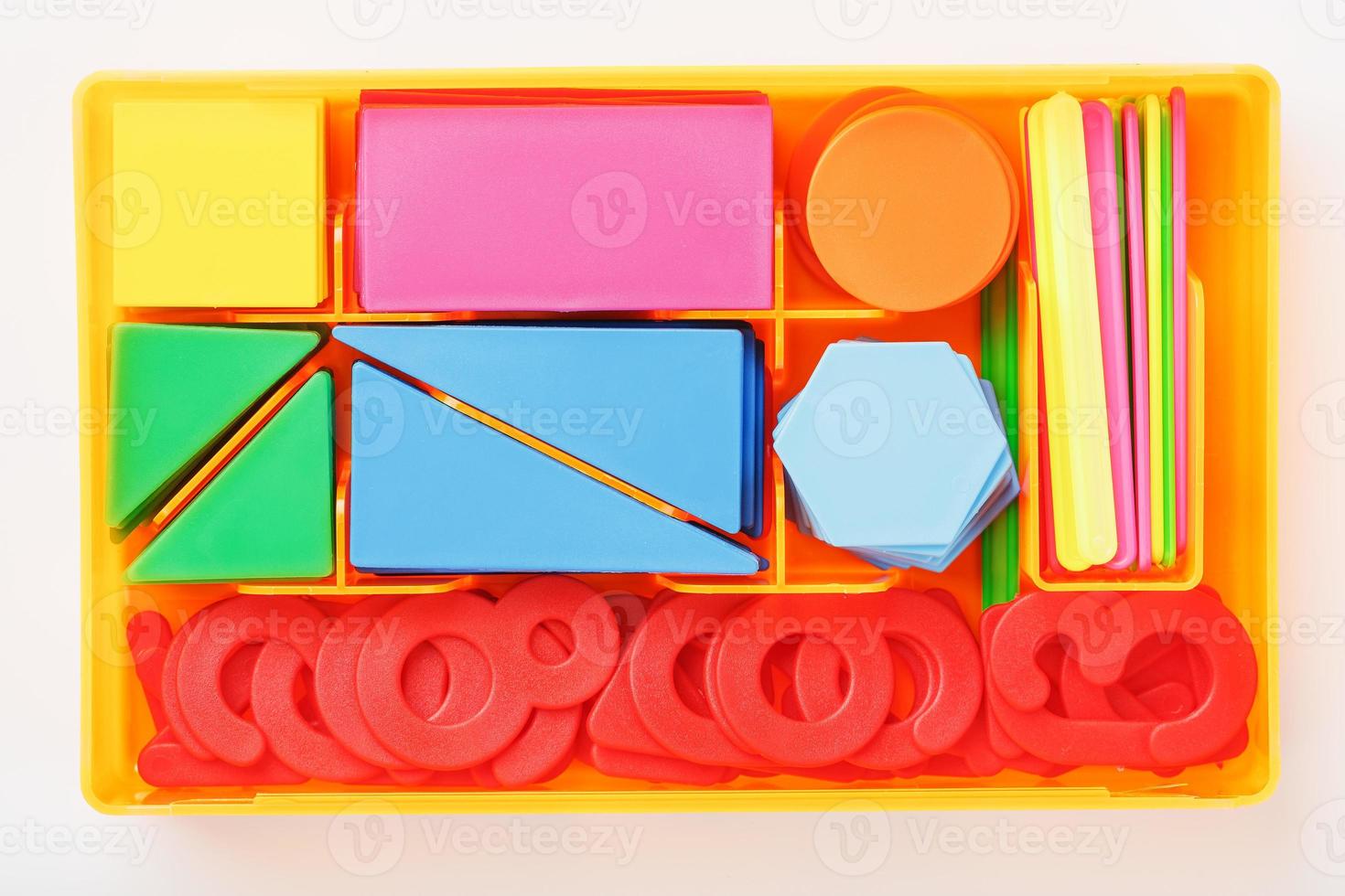 uma caixa com figuras de plástico coloridas e números em um fundo branco. jogos educativos para crianças. foto