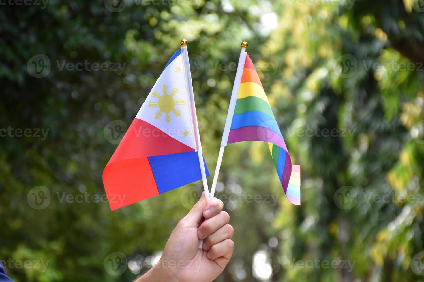 bandeira do arco-íris e bandeira nacional das filipinas segurando na mão, foco suave e seletivo, conceito para celebração do lgbtq no mês do orgulho em todo o mundo. foto